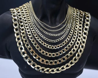 May include: A set of gold curb chains of varying widths, displayed on a black mannequin. The chains are layered from smallest to largest, with the largest chain being the thickest and most prominent.