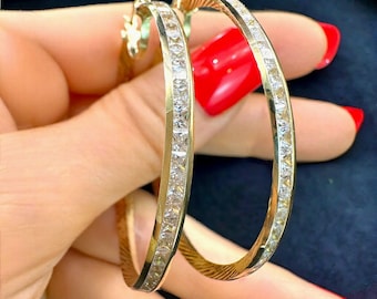 May include: Gold hoop earrings with a row of clear cubic zirconia stones around the edge.