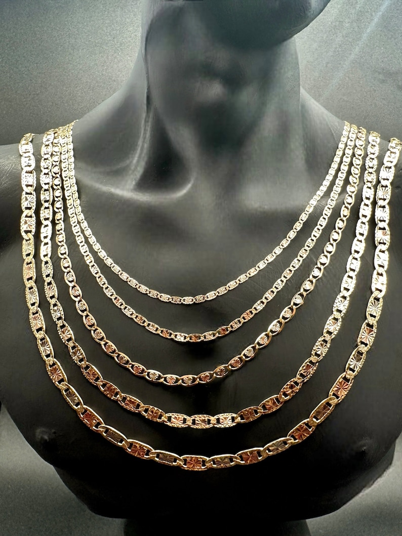 May include: A set of six gold chains with different lengths and widths. The chains are made of a shiny metal and have a textured design.