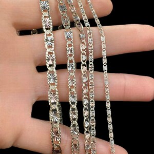 May include: Five gold chains of different widths and styles, all featuring a diamond-cut design. The chains are arranged in a row, with the widest chain at the top and the narrowest chain at the bottom.