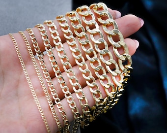 May include: A set of gold chain necklaces of varying widths and lengths. The chains are arranged in a fan shape, with the widest chain at the top and the thinnest chain at the bottom.