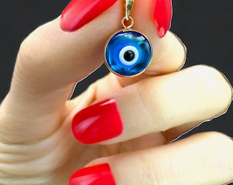 May include: A gold pendant with a blue evil eye charm. The charm has a white center and a black pupil.