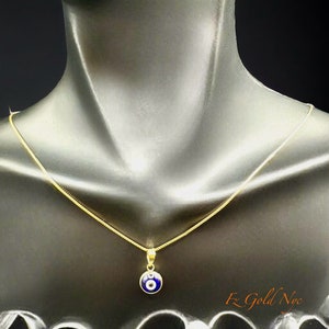Puede incluir: Un collar de cadena de oro con un colgante azul de ojo turco. El colgante es redondo y tiene un centro blanco. El collar est&aacute; en un maniqu&iacute; negro.