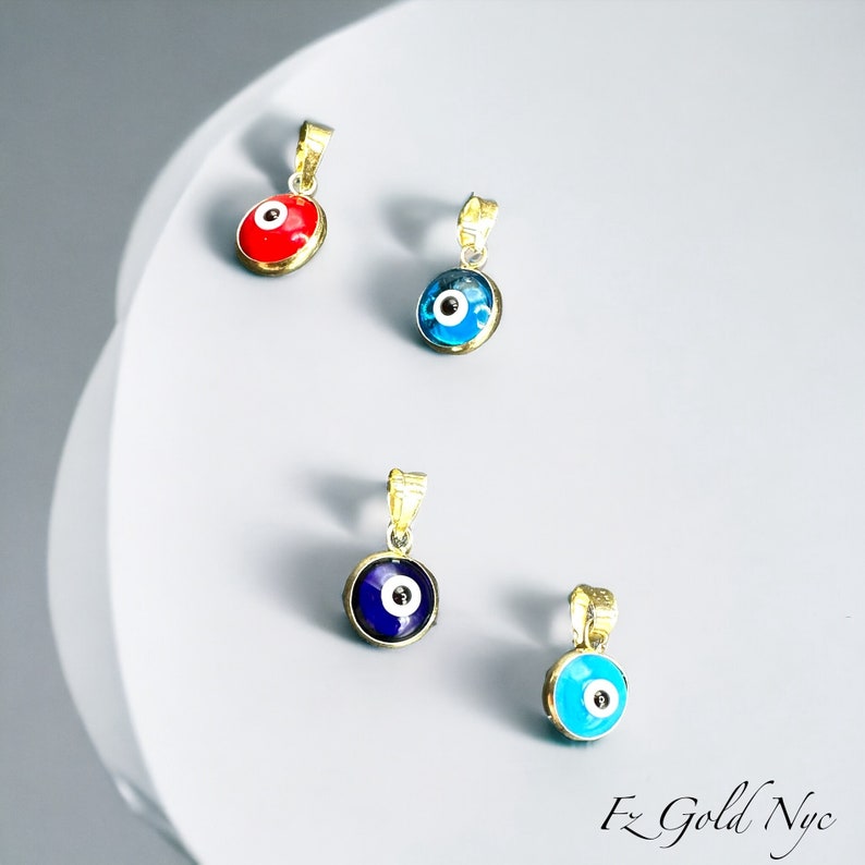 Puede incluir: Cuatro colgantes de oro con amuletos de ojo turco azul y blanco. Un colgante tiene un amuleto de ojo turco rojo.