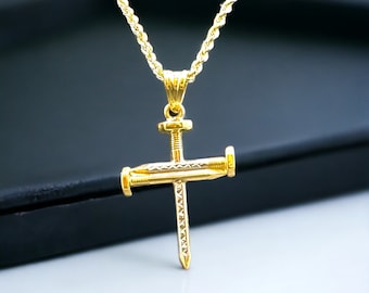 May include: A gold-colored pendant necklace featuring a cross design made of stylized nails. The nails are arranged to form a cross shape, with a screw head at the top. The necklace chain is a twisted rope style.