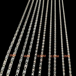 May include: Five silver chains of different widths, ranging from 2mm to 5mm. The chains are all made of a silver metal with a polished finish. The chains are arranged in order of size, with the smallest chain on the right and the largest chain on the left.