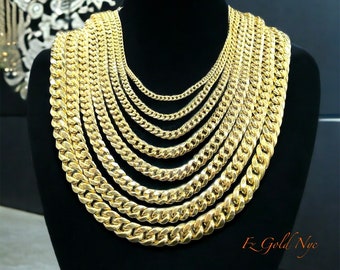 May include: A display of gold-colored chain necklaces of varying thicknesses, arranged in a layered presentation. The chains are displayed on a black mannequin, showcasing the different sizes and styles. The text "Fz Gold Nyc" is visible.
