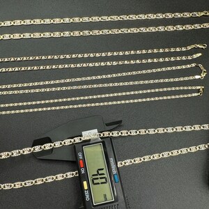 May include: A set of six gold chains of varying lengths, with a digital caliper measuring one of the chains at 4.8 mm. The chains are on a black surface.