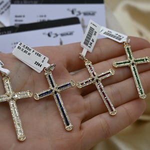 Puede incluir: Cuatro colgantes de cruz de oro con piedras preciosas de diferentes colores. Las cruces est&aacute;n adornadas con peque&ntilde;os diamantes. Los colgantes est&aacute;n etiquetados con informaci&oacute;n sobre el peso en quilates y la claridad. D: 0,62 ct F VSSI 0 2244, D: 0,80 ct F VSSI 0 3171, 3,04 ct, 0,80 ct.
