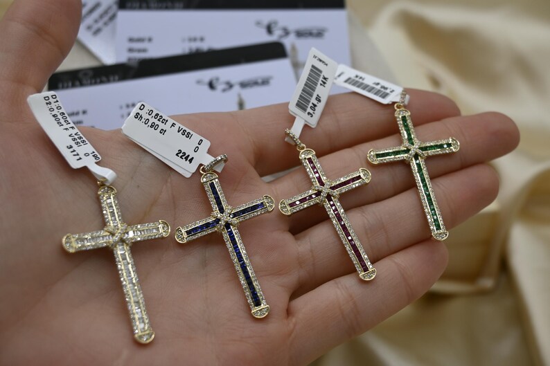 Puede incluir: Cuatro colgantes de cruz de oro con piedras preciosas de diferentes colores. Las cruces est&aacute;n adornadas con peque&ntilde;os diamantes. Los colgantes est&aacute;n etiquetados con informaci&oacute;n sobre el peso en quilates y la claridad. D: 0,62 ct F VSSI 0 2244, D: 0,80 ct F VSSI 0 3171, 3,04 ct, 0,80 ct.