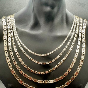 May include: A set of six gold chains with a mariner link design. The chains are layered on a mannequin's neck and vary in width.