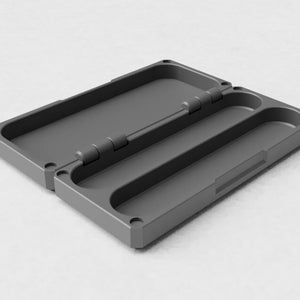 May include: A grey rectangular case with a hinged lid, open to show two curved compartments. The case has rounded corners and a matte finish. The hinge is visible, and the case appears to be made of a durable material.