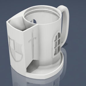 Puede incluir: Taza de cerámica blanca con forma de castillo con un diseño de espada y escudo. La taza tiene un asa y un compartimento separado para guardar objetos.