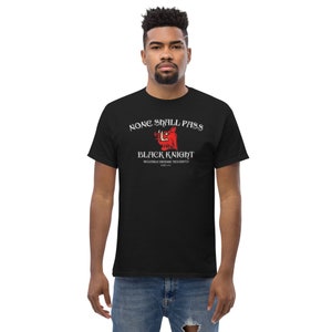 May include: Black t-shirt featuring a red boar graphic with the text "None Shall Pass" above and "Black Knight" below. The text "Reliable Espionage Security Est. 1973" is beneath the graphic.