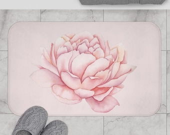 May include: A pink bath mat featuring a watercolour illustration of a large pink peony flower.