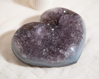 May include: A heart-shaped amethyst geode with a purple crystal interior and a light blue outer layer.