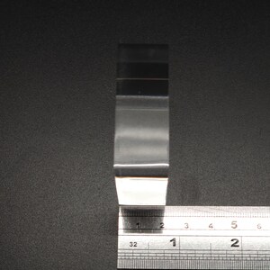 Puede incluir: Una pieza de pl&aacute;stico transparente rectangular, de aproximadamente 5 cm de largo, se mide con una regla. La regla est&aacute; marcada en cent&iacute;metros y mil&iacute;metros.