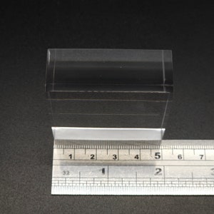 Puede incluir: Un bloque de acr&iacute;lico transparente que mide 12,7 cm de largo. El bloque est&aacute; sobre una regla para la escala.