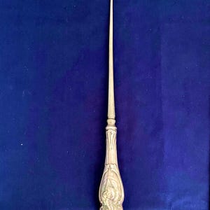 Peut inclure: Un tire-bottes en argent avec une poignée ornée. La poignée est décorée d'un motif floral.