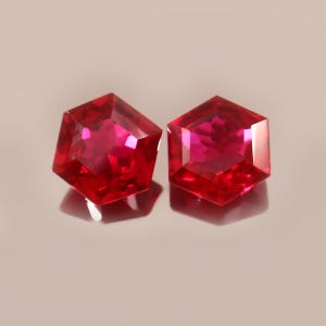 May include: Two red hexagonal gemstones with a faceted cut.