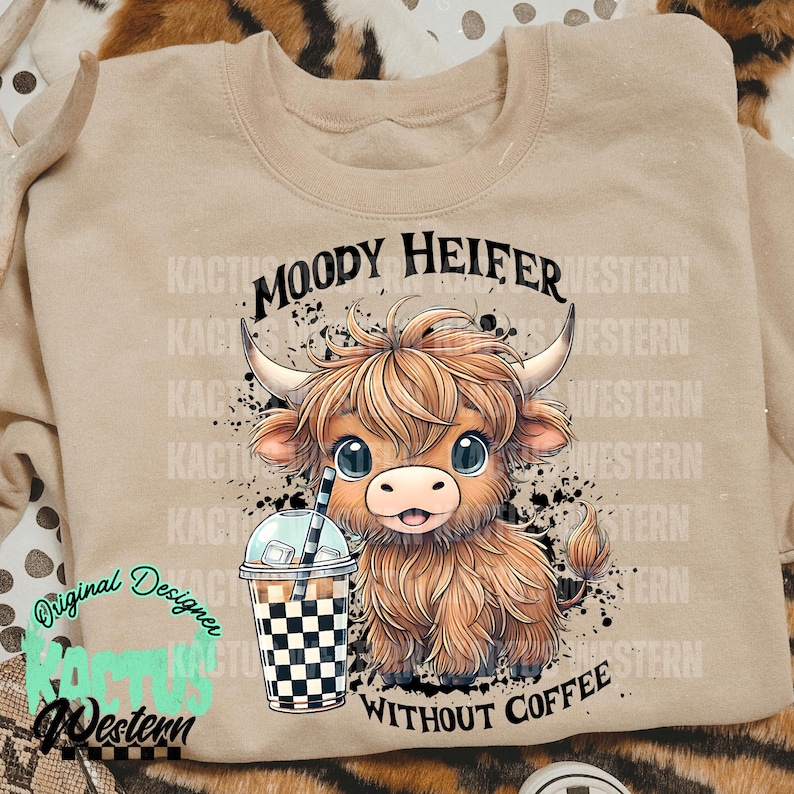 May include: A tan sweatshirt with a black and white graphic of a cartoon Highland cow with the text "Moody Heifer Without Coffee".