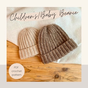 Könnte beinhalten: Zwei gehäkelte Mützen, eine beige und eine braune, auf einer Holzoberfläche. Der Text "Children's/Baby Beanie" ist über den Mützen geschrieben. Der Text "PDF crochet pattern" ist unter den Mützen geschrieben.