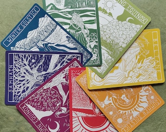 May include: A collection of eight rectangular cards featuring white line art illustrations on colored backgrounds. Each card displays a seasonal theme with text: Winter Solstice, Imbolc, Spring Equinox, Beltane, Summer Solstice, Lughnasadh, Autumn Equinox, and Samhain.