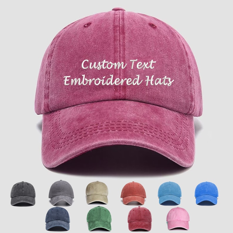 K&ouml;nnte beinhalten: Eine Auswahl von 10 verschiedenen farbigen Baseballkappen mit dem Text "Custom Text Embroidered Hats" auf der Vorderseite der burgunderfarbenen Kappe.