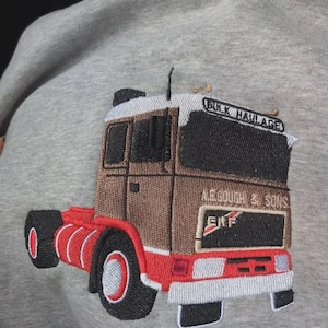 May include: A heather gray sweatshirt featuring an embroidered design of a brown and red semi-truck. The truck cab displays the text "BULK HAULAGE" above the windshield and "A.E. GOUGH & SONS" with the "ERF" logo printed on the front panel.