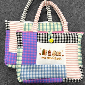 Könnte beinhalten: Zwei gesteppte Tragetaschen mit einem Patchwork-Design aus rosa, blau, lila sowie schwarz-weiß karierten und gestreiften Stoffen. Ein weißer rechteckiger Aufnäher zeigt eine gestickte Kerze, Bücher und den Text one more chapter.