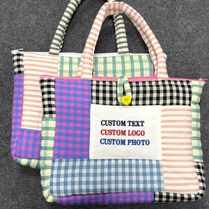 Könnte beinhalten: Zwei gesteppte Tragetaschen mit einem Patchwork-Design aus verschiedenen Vichy-Karos und Streifenmustern in Rosa, Blau, Schwarz und Weiß. Ein weißer rechteckiger Aufnäher auf der Vorderseite zeigt den Text CUSTOM TEXT, CUSTOM LOGO und CUSTOM PHOTO.