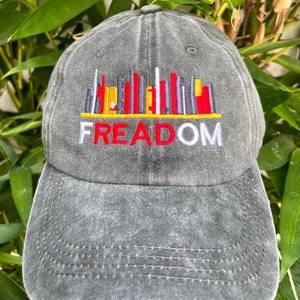 May include: A black denim baseball cap with an embroidered cityscape and the word "FREEDOM" in red, white, and blue.