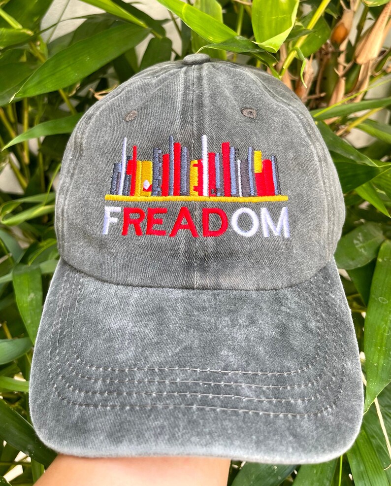 May include: A black denim baseball cap with an embroidered cityscape and the word "FREEDOM" in red, white, and blue.