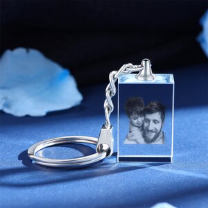 May include: A silver keychain with a clear crystal charm. The charm has a photo of a father and son inside. The photo is in black and white.