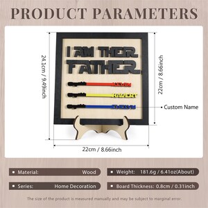 Puede incluir: Un letrero de madera con el texto "I am their father" en letras negras. El letrero tiene un marco negro y un soporte de madera. Hay tres sables de luz con nombres escritos en ellos: Kevin, Havert y Evelyn. El letrero mide 24,1 cm de alto y 22 cm de ancho.