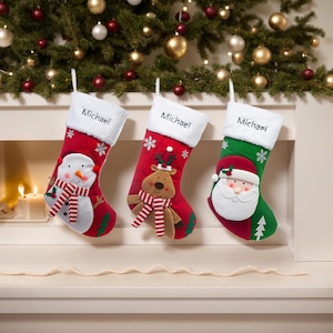 May include: Three Christmas stockings with white cuffs, each personalized with the name "Michael." The red stockings feature a snowman, reindeer, and Santa Claus design. Festive holiday decor.