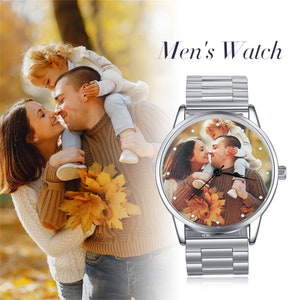 May include: A silver watch with a round face and a metal band. The watch face has a photo of a family of three, a man, a woman, and a child, with fall foliage in the background. The text "Men's Watch" is displayed above the watch.