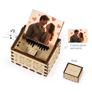 Pu&ograve; includere: Un carillon in legno con una foto personalizzata di una coppia e accenti a forma di cuore rosso. La scatola presenta un design a tasti di pianoforte e note musicali. &Egrave; visibile anche una scatola pi&ugrave; piccola con il testo "I love you".
