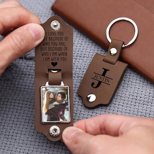 May include: Two brown leather keychains. One keychain features a photo and the engraved text: "I LOVE YOU...WHO I AM WHEN I AM WITH YOU." The other keychain has the name "JUSTIN" and the initial "J" engraved.