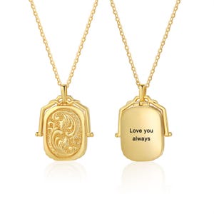 May include: A gold-colored locket necklace with a delicate chain. The front of the locket features an ornate floral design, while the back is engraved with the words "Love you always". The locket is rectangular with rounded edges.