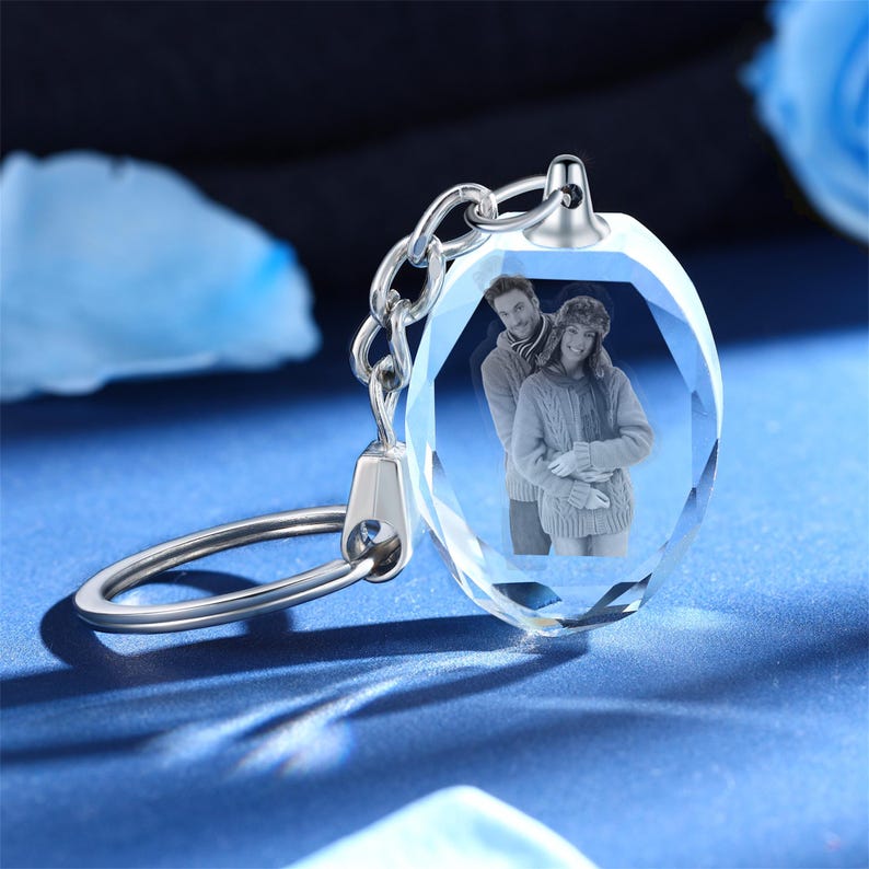 May include: A silver keychain with a crystal charm featuring a photo of a couple. The crystal is faceted and has a clear, transparent appearance.
