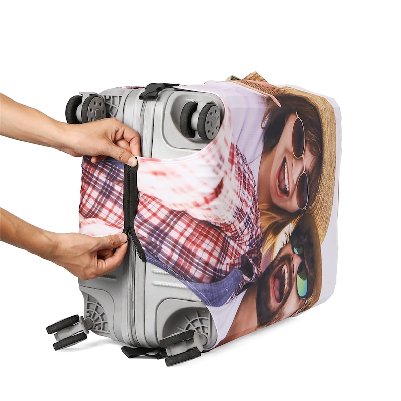 May include: A gray suitcase with a zippered cover featuring a photo of a couple smiling and wearing sunglasses. The cover is a white background with a red and white plaid pattern.