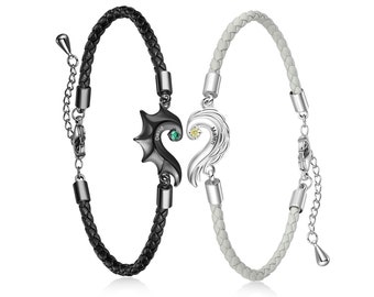 May include: A pair of matching leather bracelets with a heart-shaped charm. The black bracelet has a silver charm with the name "David" and a green stone. The white bracelet has a silver charm with the name "Maren" and a yellow stone.