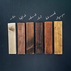May include: Seven wood samples stained in different colors, labeled from left to right: no stain, light oak, medium oak, walnut, dark rosewood, antique pine.