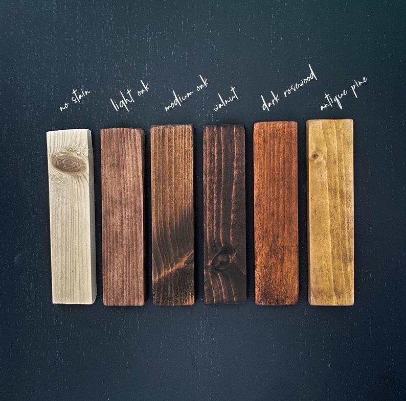 May include: Seven wood samples stained in different colors, labeled from left to right: no stain, light oak, medium oak, walnut, dark rosewood, antique pine.