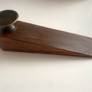 May include: A dark brown wooden doorstop with a brass knob on top.