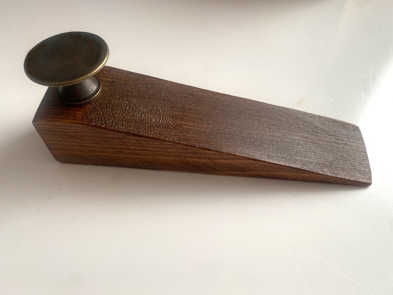 May include: A dark brown wooden doorstop with a brass knob on top.