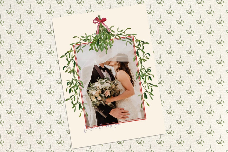 May include: A wedding photo of a couple kissing under a sprig of mistletoe with a red ribbon. The photo is framed with a red dotted line and surrounded by a green mistletoe pattern.