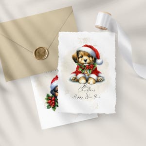 May include: Christmas greeting cards featuring a watercolor illustration of a puppy wearing a Santa hat and red coat. The cards have the text "Merry Christmas & Happy New Year". A beige envelope with a gold seal and white ribbon are also in the image.