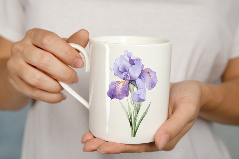K&ouml;nnte beinhalten: Eine wei&szlig;e Keramiktasse mit einem Design aus einer lila und gelben Iris-Blume.